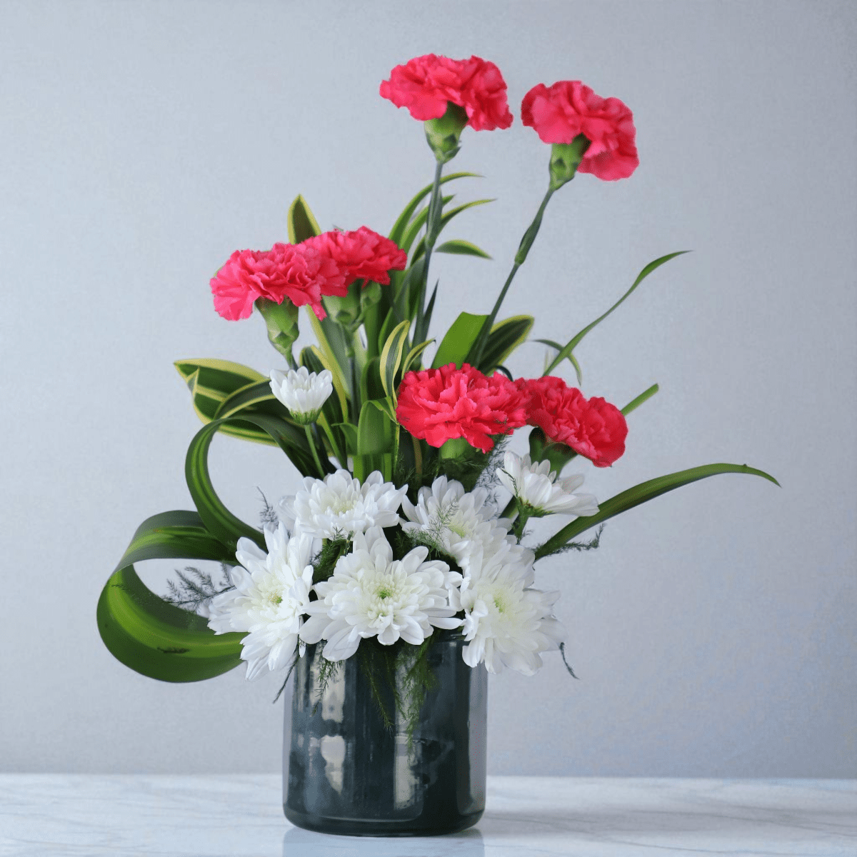 Carnation and daisy flower vase arrangement with greenery