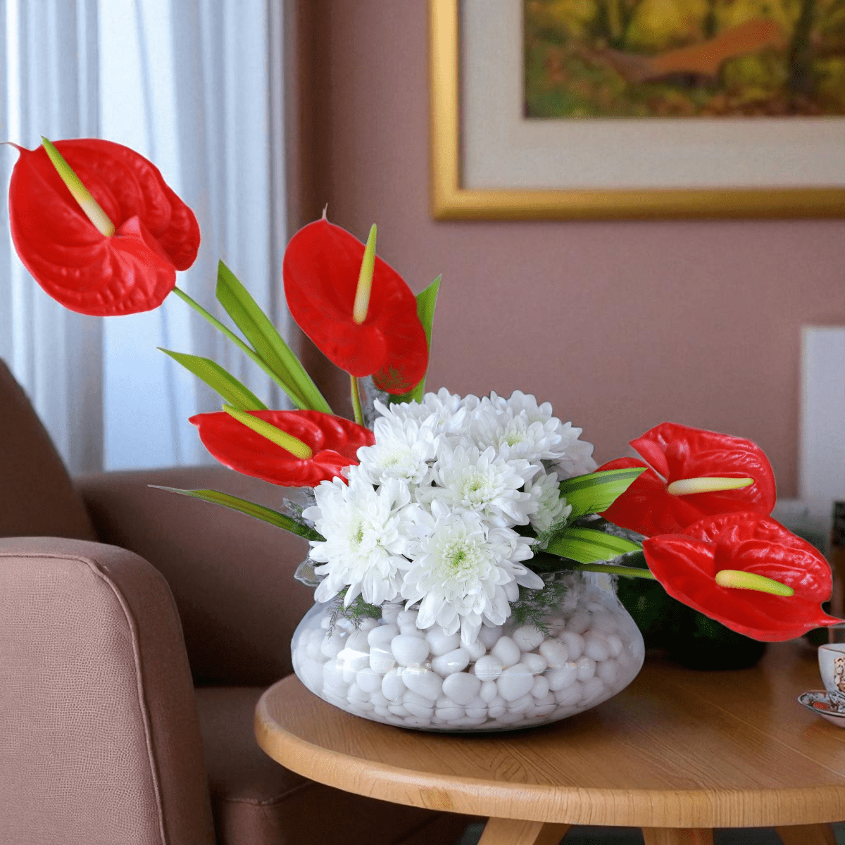 Red anthurium and white daisy vase arrangement with decorative stones