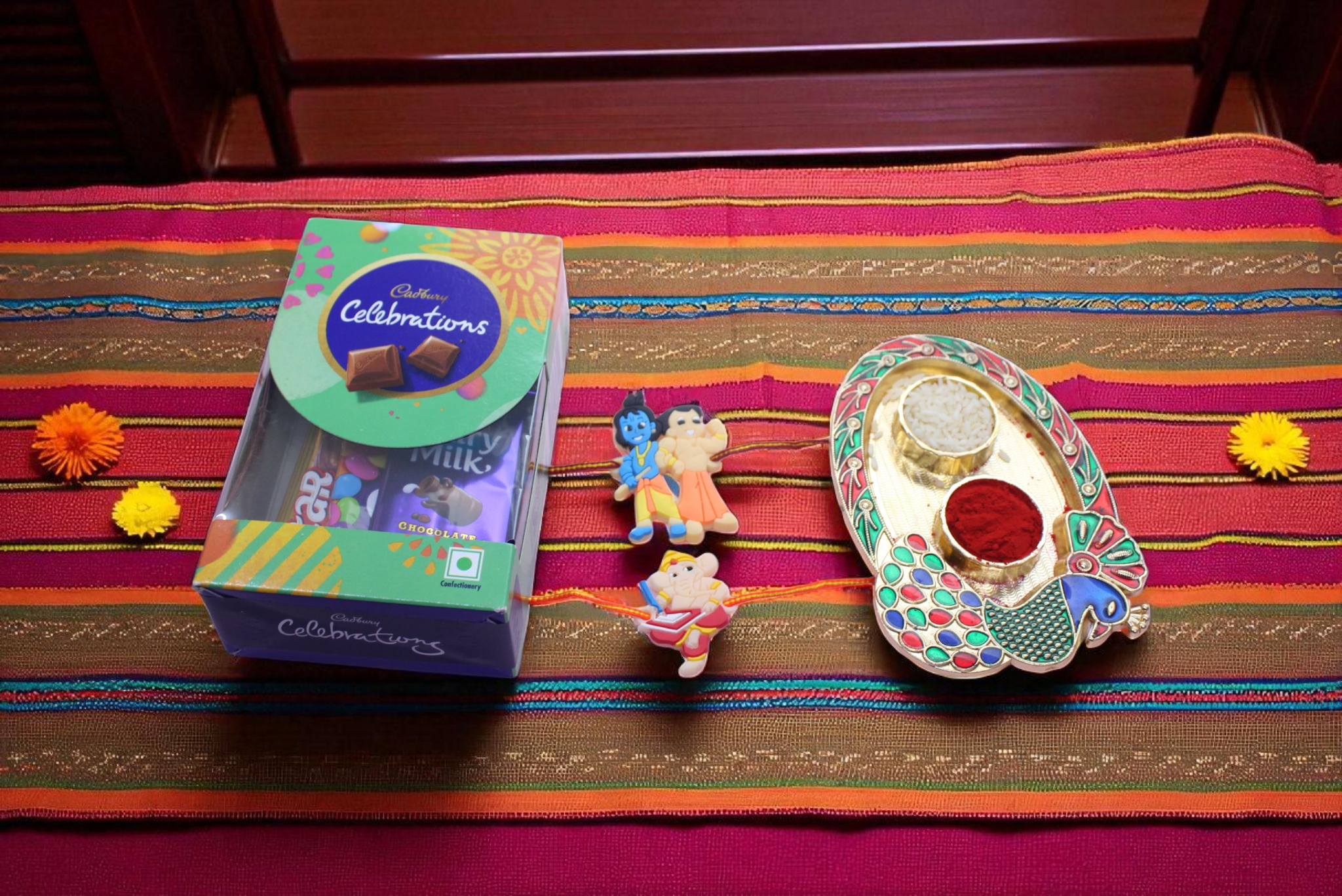 2 adorable kid-themed Rakhis (Krishna & Ganpati designs), a Cadbury Celebration chocolate box - YHOJA.COM