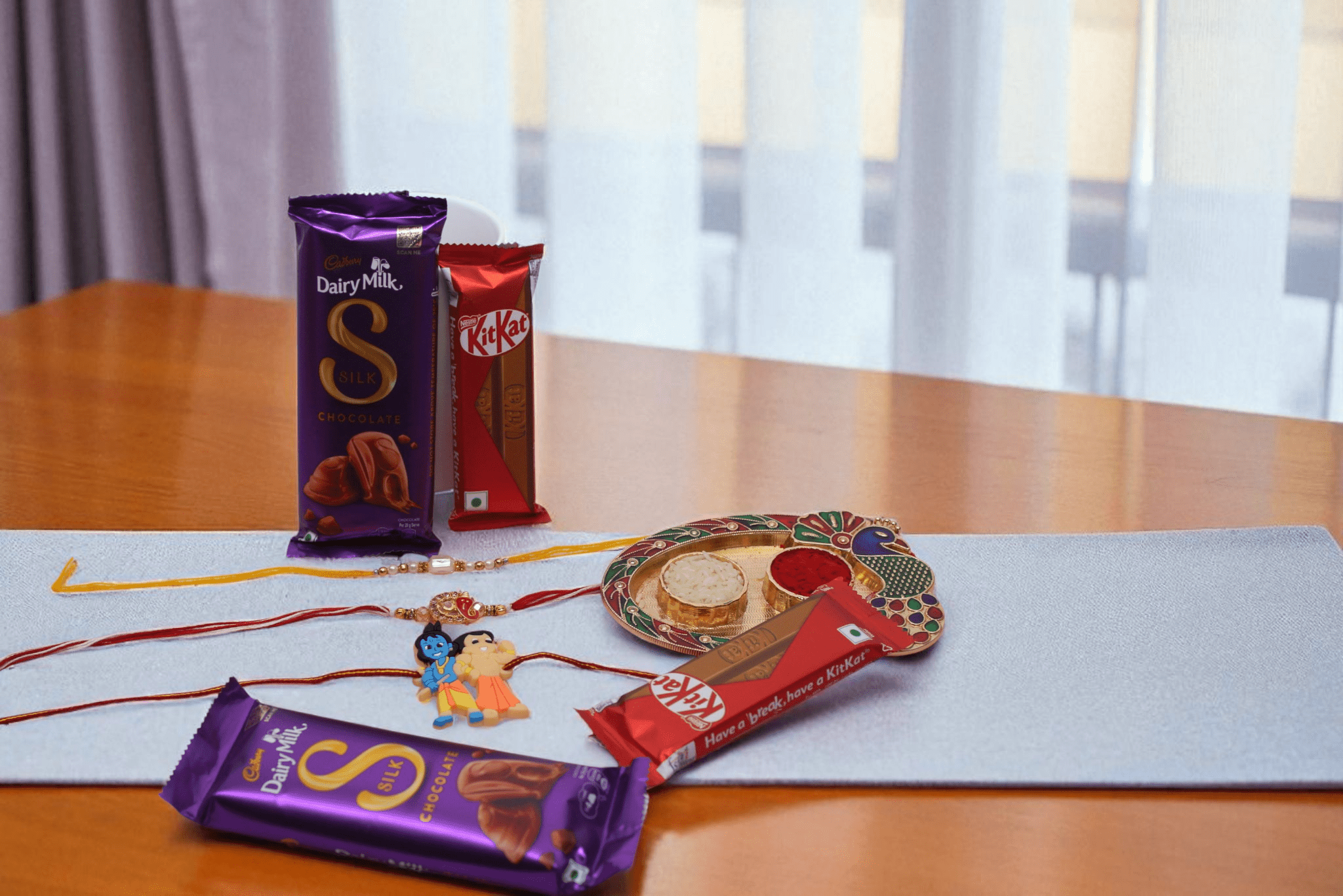 Trio Chocolate Rakhi Hamper with Ganpati Rakhi, Kid Krishna Rakhi, Pearl Rakhi, Dairy Milk Silk and KitKat Bars