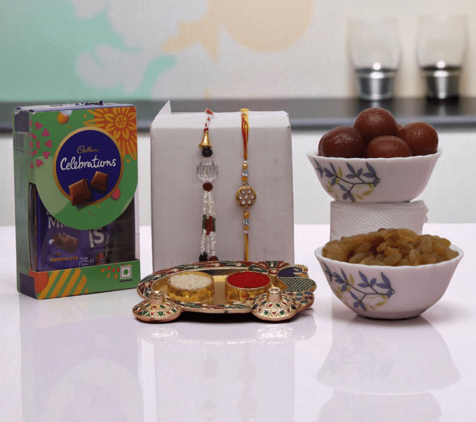 Couple Rakhi Sweet Hamper with Gulab Jamun, Cadbury Celebrations, Raisins and Lumba Rakhi