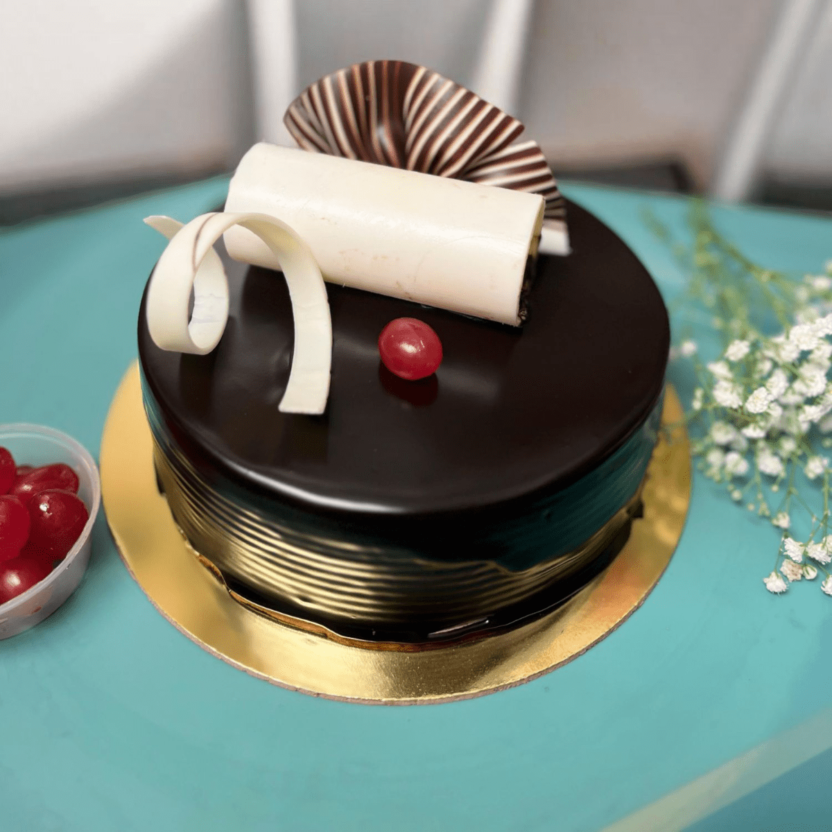 Glossy Truffle Elegance Cake with chocolate glaze, cherry topping & white chocolate rolls