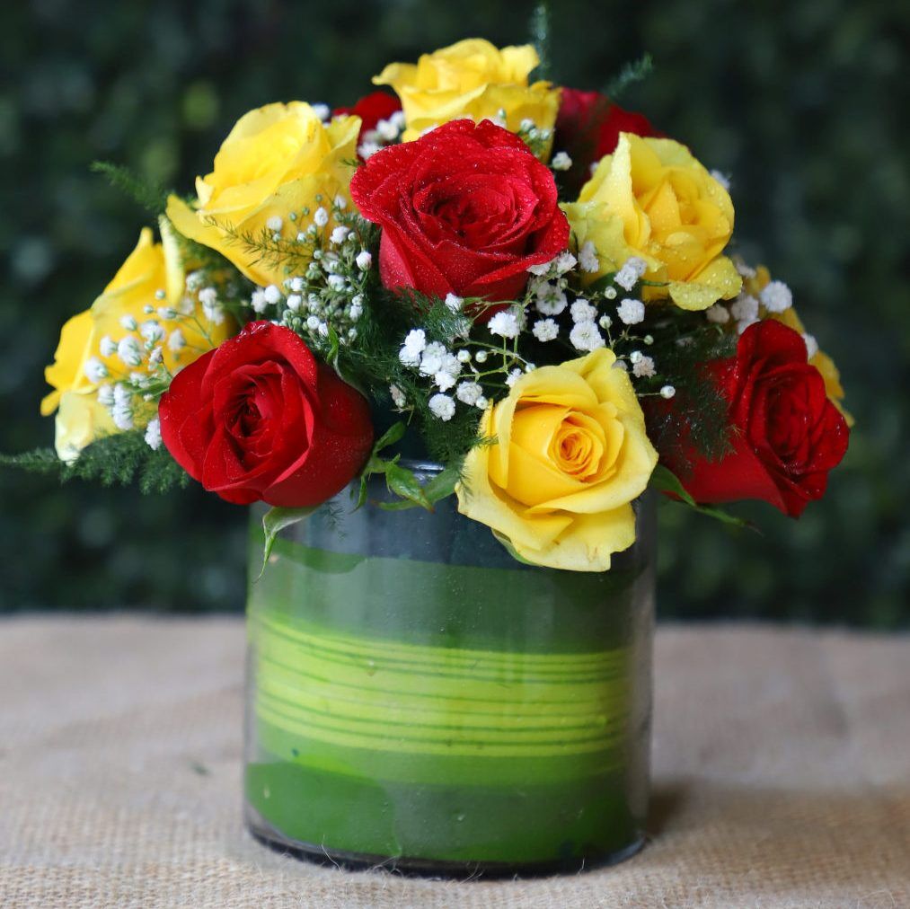 15 red and yellow roses arranged in a round glass vase with fillers – YHOJA.COM flower gift